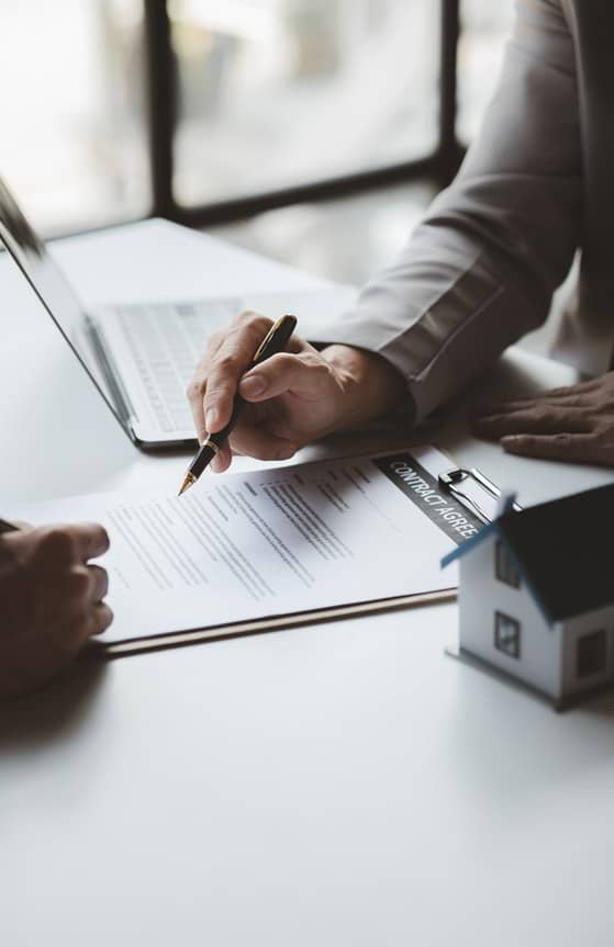 Investor reviewing and signing loan documents beside a model home